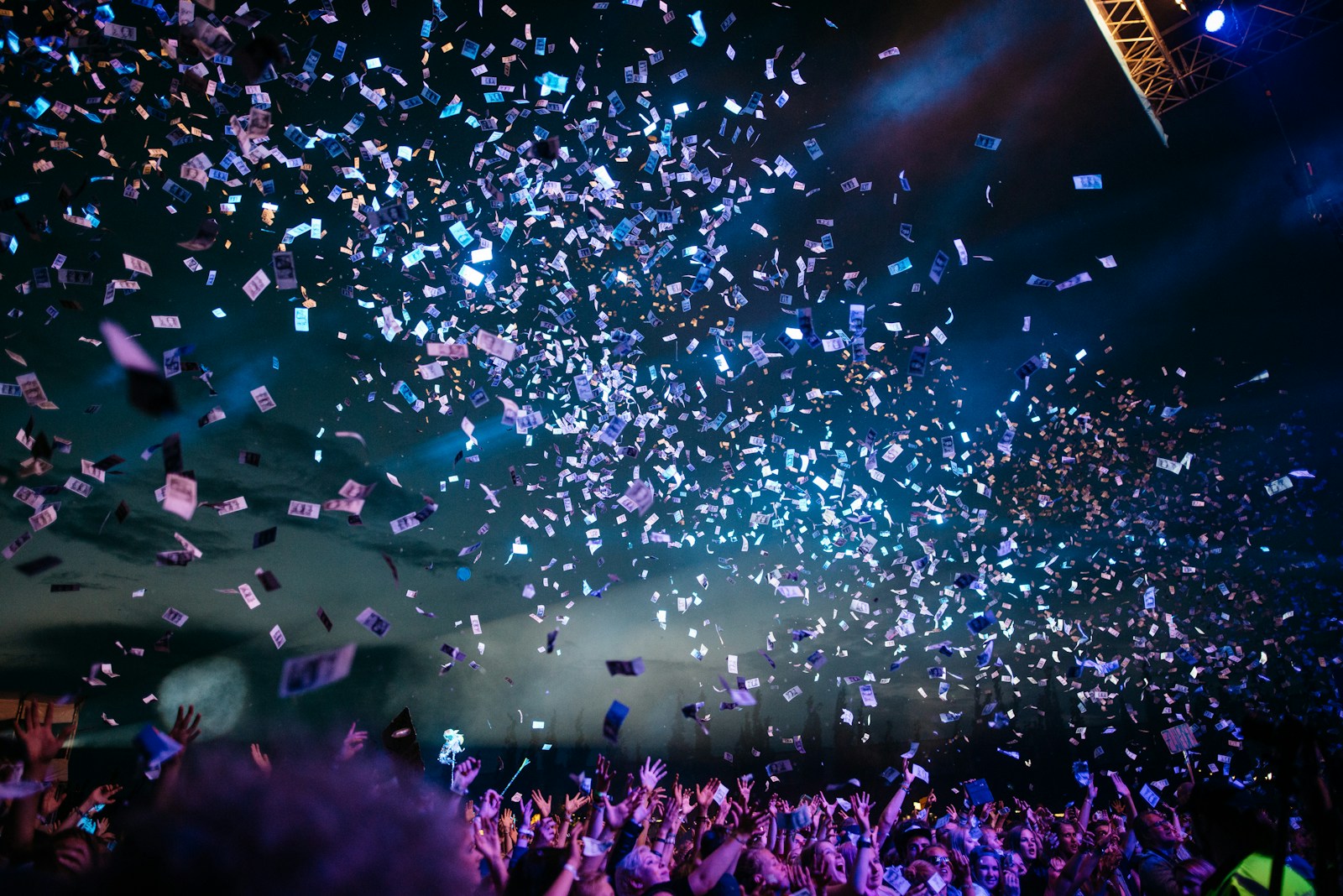 A festival crowd under stage lights and falling confetti